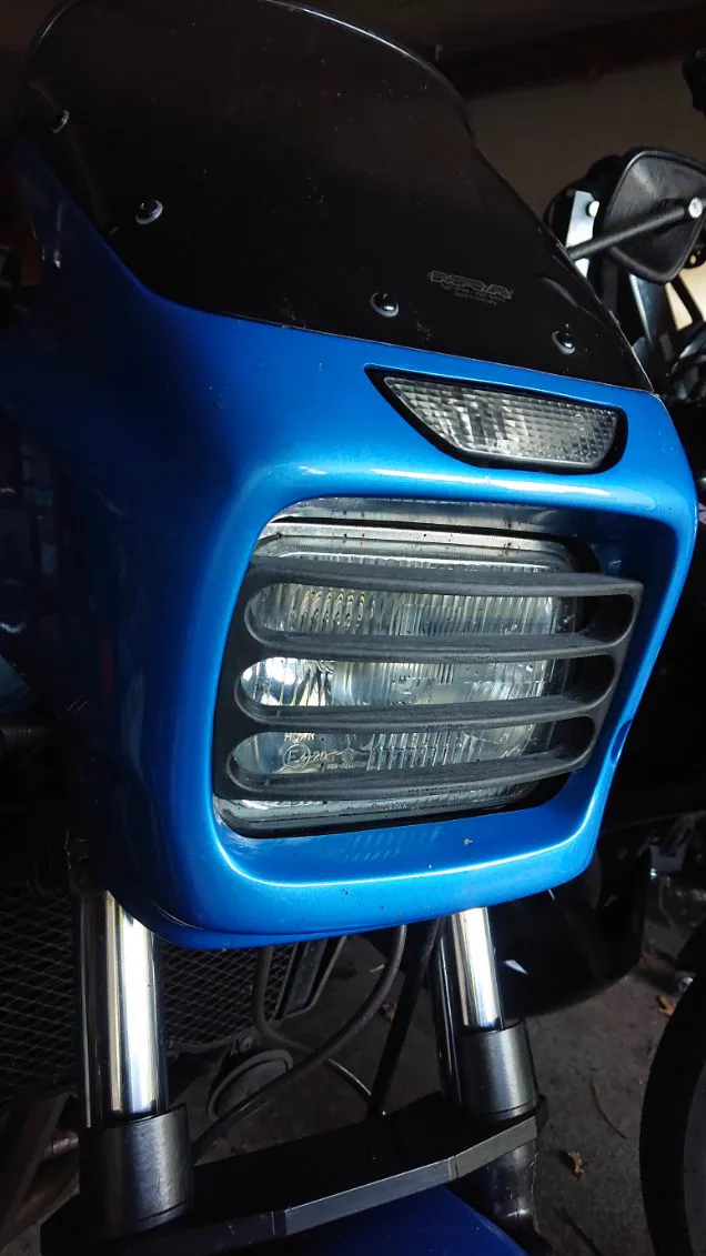 Grille de phare imprimée en 3D, montée sur le carénage bleu d’une moto